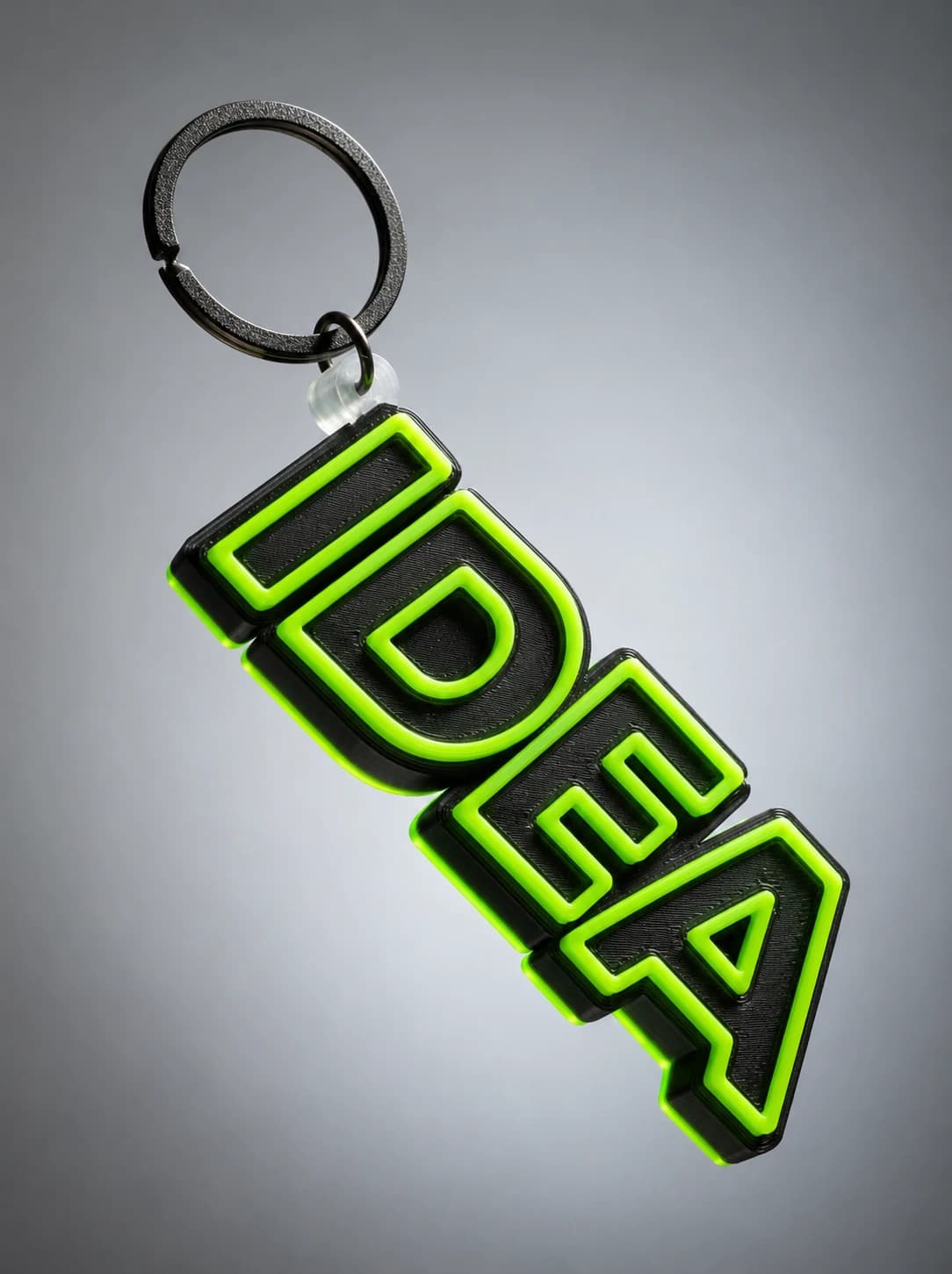 A 3D-printed IDEA name keychain in black with neon green outlines